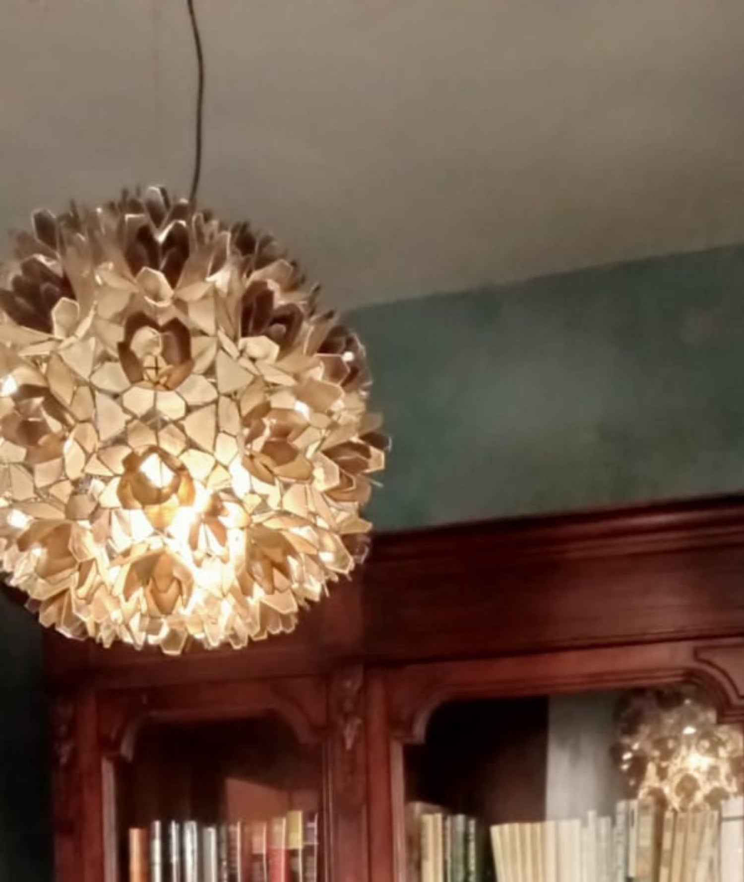 Decorative ceiling light fixture in a room with bookshelves.