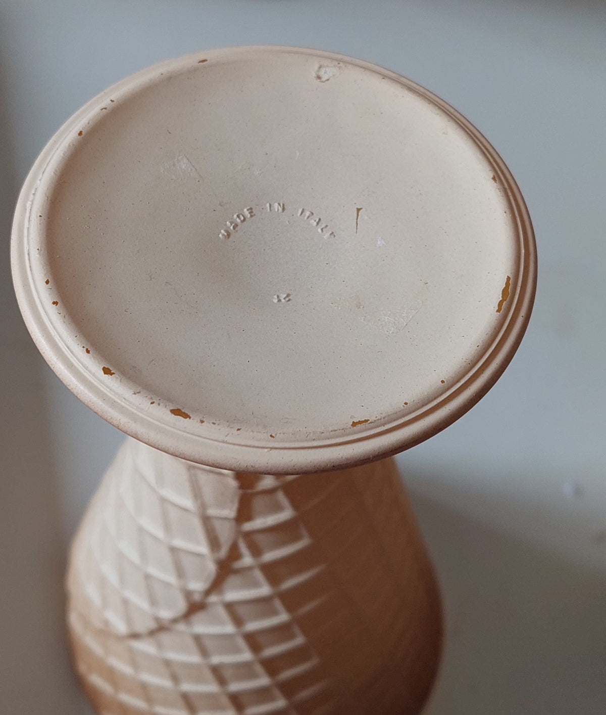 Ceramic vase with a textured surface and 'Made in Italy' inscription on a neutral background