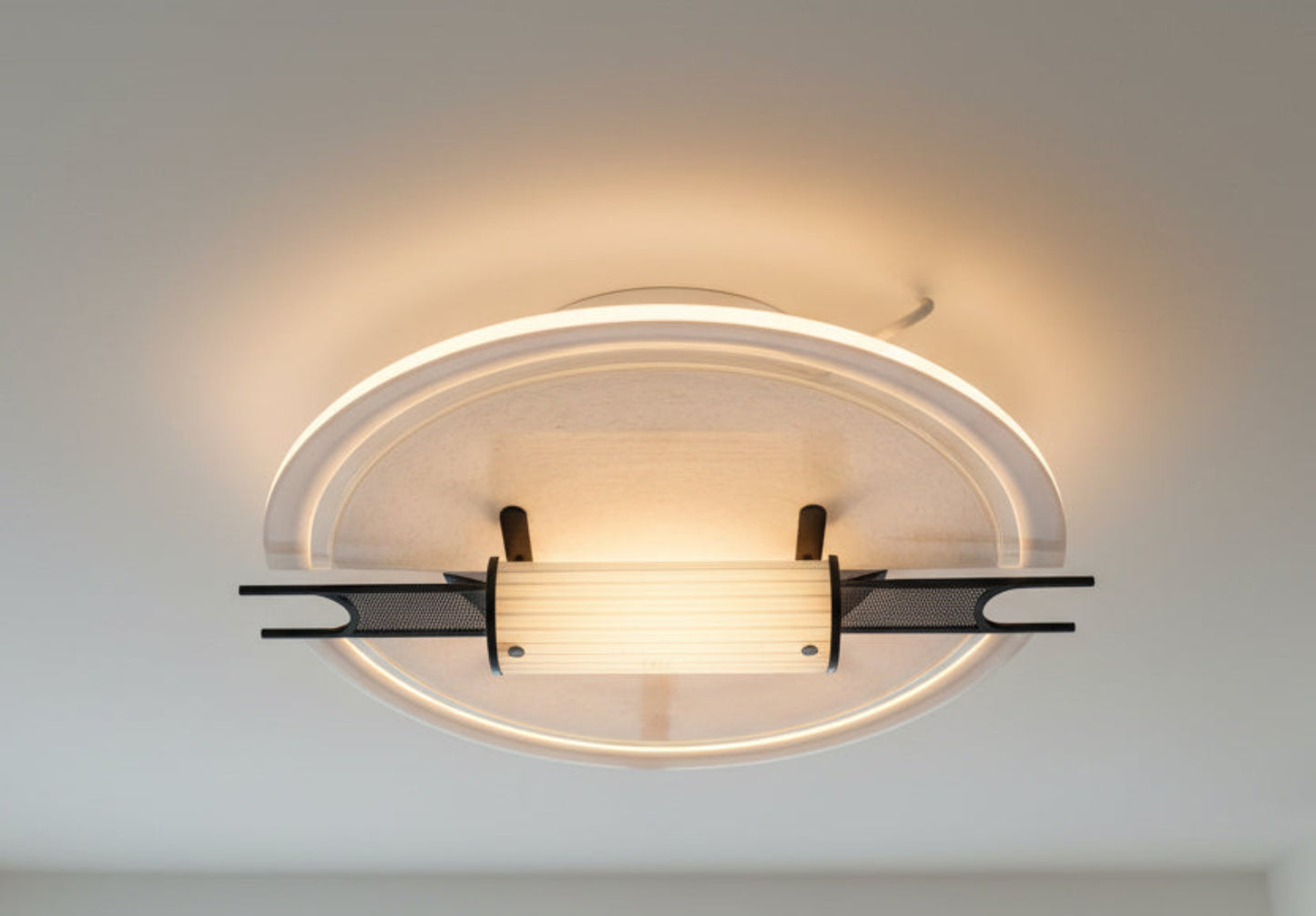 Modern ceiling light fixture with glass shade on a neutral background
